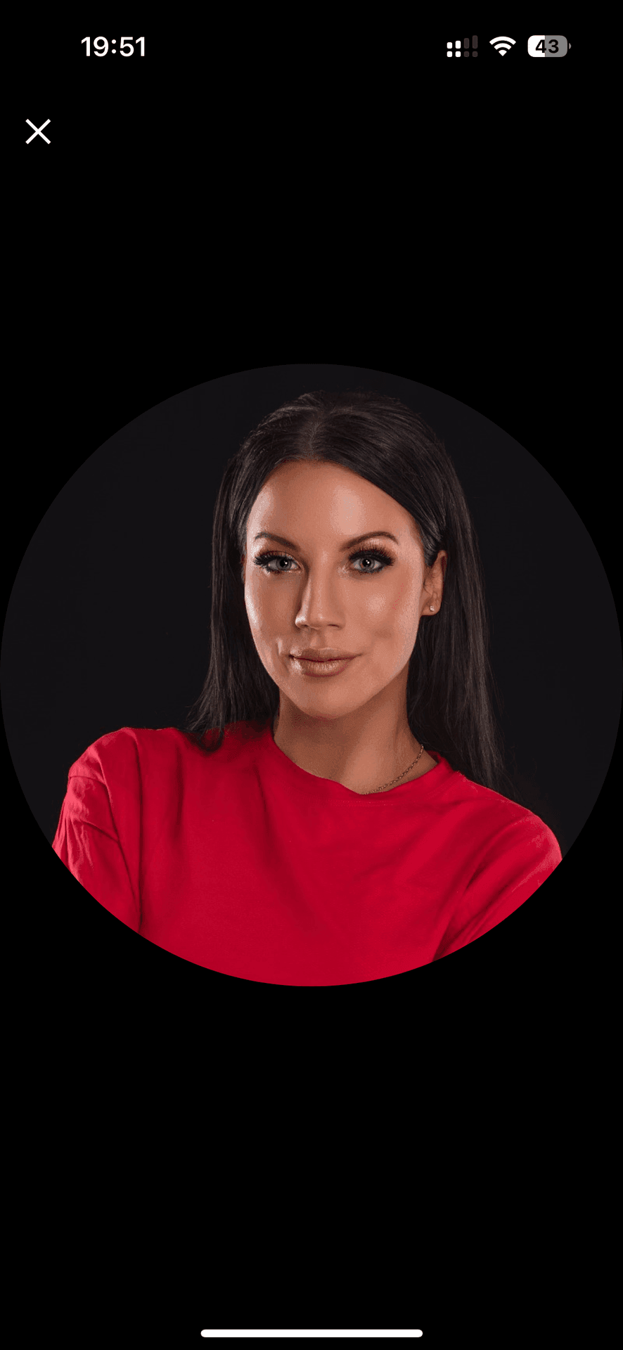 Woman in a red top against a dark background.