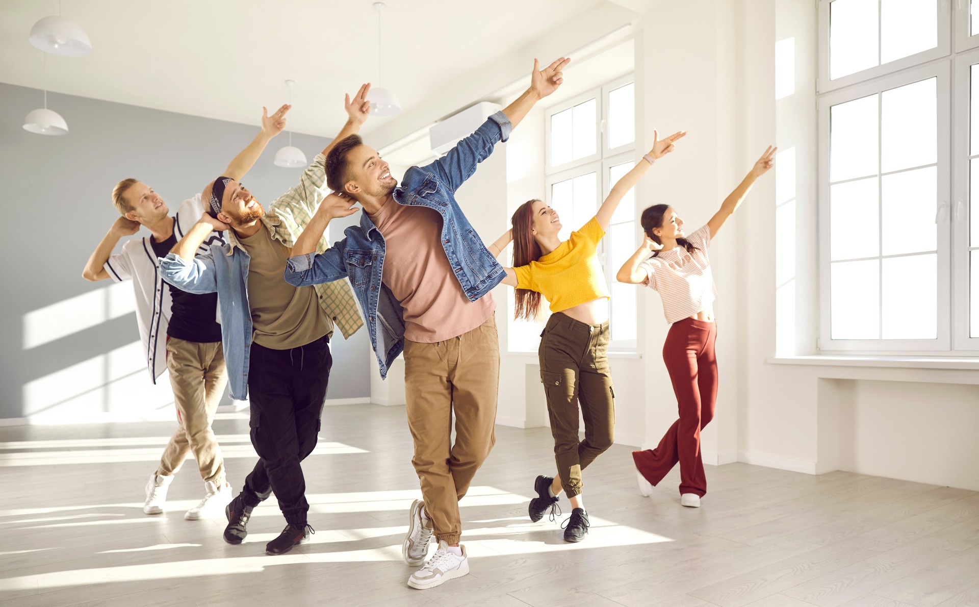 Happy energetic young hip-hop dancers dance together in bright spacious dance studio.