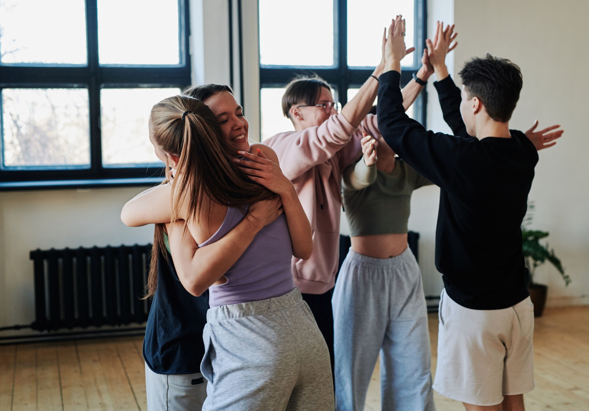 Group of contemporary teenage friends giving hugs and high five to each other